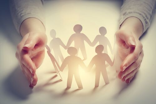 A women holding her hands apart with a paper ring of people holding hands in the middle