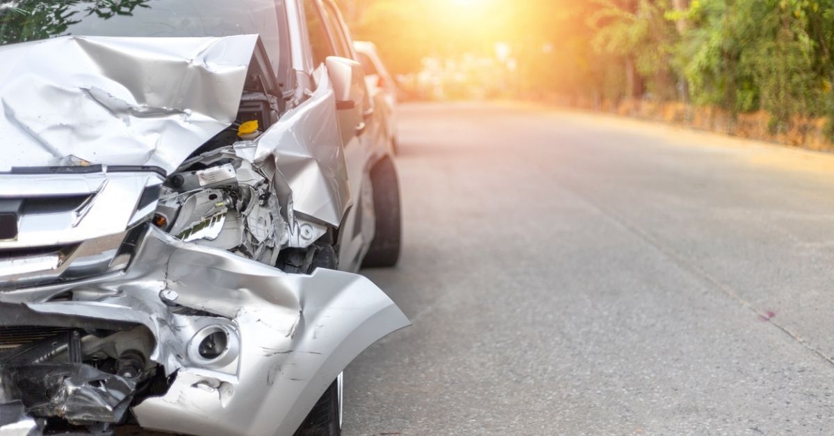 close up of silver car with smashed front bumper