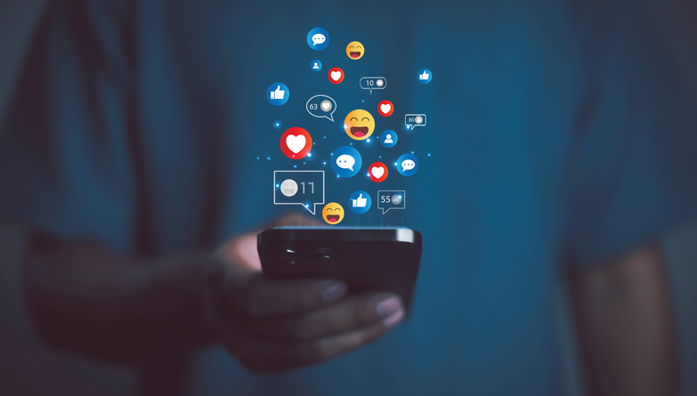 Person using smartphone with social media icons, likes, hearts, and emojis floating, symbolizing online communication, digital marketing, social network engagement, and modern lifestyle. stock photo